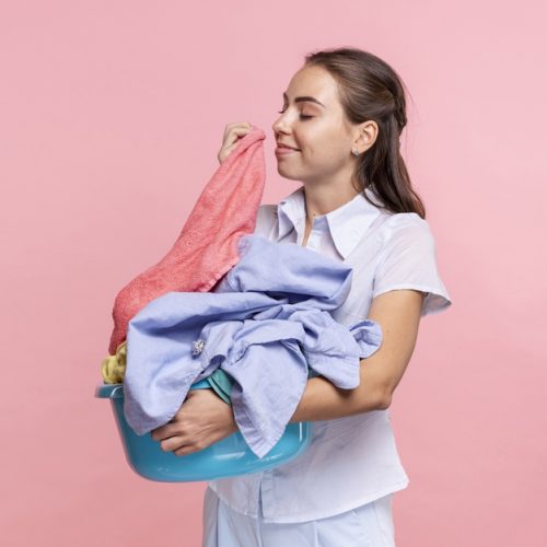 medium-shot-smiley-woman-smelling-clean-clothes_23-2148246495