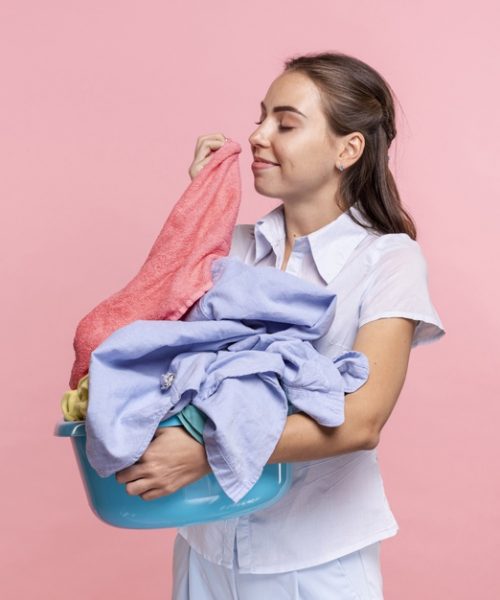 medium-shot-smiley-woman-smelling-clean-clothes_23-2148246495